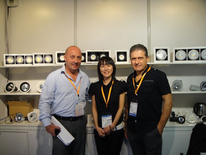Three people standing in front of the lighting display shelves.