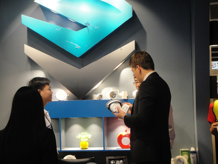 Two people talking in front of the illuminated KAIFON display.