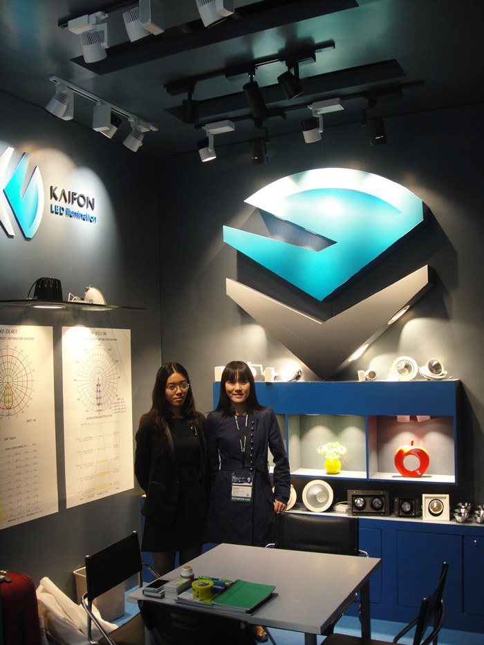 Two people standing near the illuminated display wall.