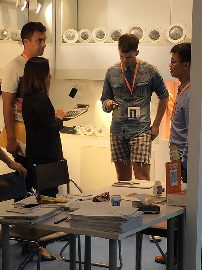 People examining items on a table beside the lighting display.