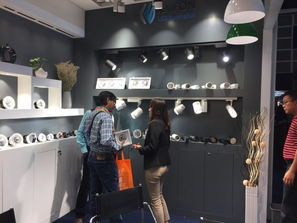 People talking in front of track lights and downlight display shelves.