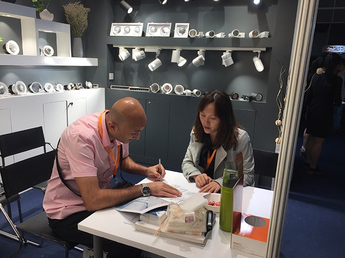 Two people reviewing papers at a table inside the KAIFON stand.