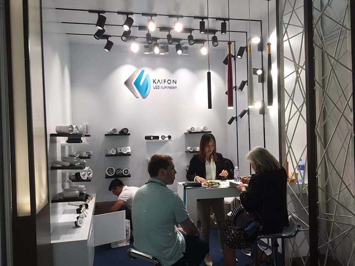 People meeting at a table beside the KAIFON lighting display.