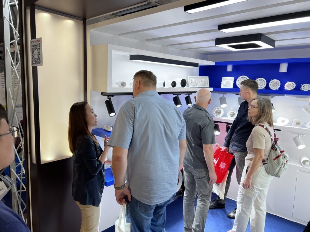 People talking beside lighting display shelves at the KAIFON stand.